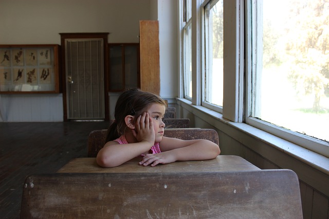 Little girl lost in thought in a classroom